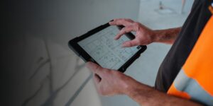 A contractor reviews construction project drawings on a tablet.